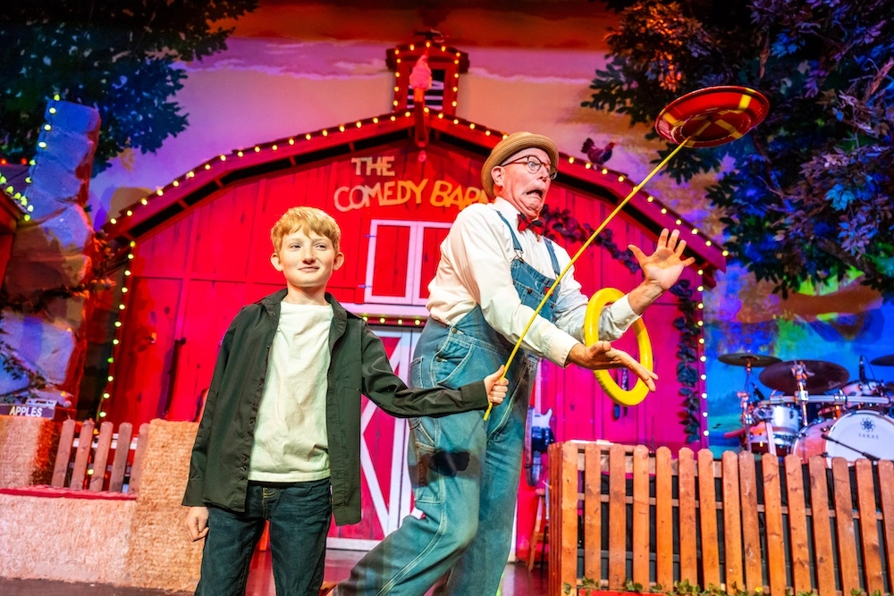 Kid performing a trick with a Comedy Barn performer